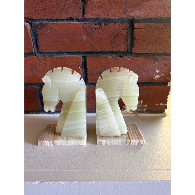 Striking vintage bookends carved from banded onyx, featuring stylized horse head (chess knight) forms. The natural stone...