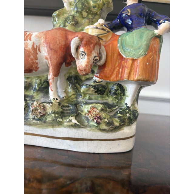 Antique Victorian Staffordshire flatback figure of a milkmaid in period dress leaning on her milk bucket next to a cow...