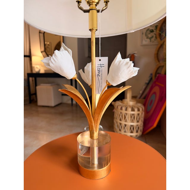 This contemporary glam table lamp features a sculptural gold porcelain flower accented with crisp white detailing,...