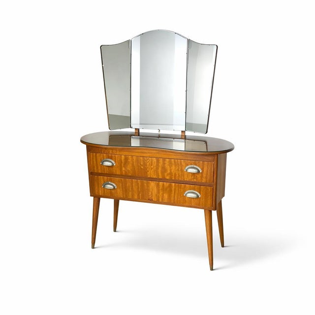 A beautifully proportioned mid-century walnut dressing table featuring an elegant tri-fold mirror and warm, figured grain...