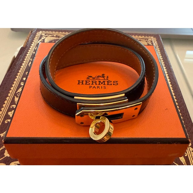 Hermès Kelly Double Tour Bracelet in black leather with brown felt bag and iconic orange logo box for storage. Double...