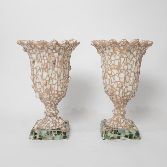 A striking pair of large-scale mosaic shell and glass urns in a dramatic trumpet form, dating to circa 1990. Each urn...
