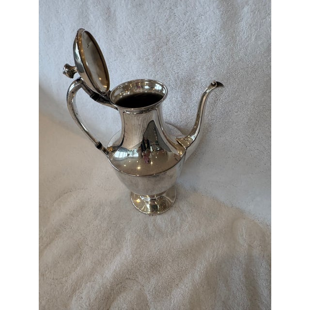 Elevate your table or décor with this elegant three‑piece vintage silverplate tea set, featuring a tall teapot, lidded...