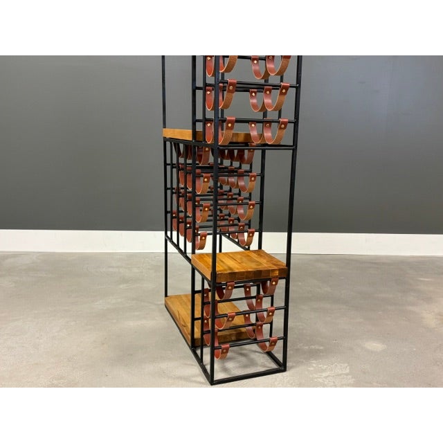 A mid century modern iron frame wine rack with brand new leather straps to hold 40 bottles of wine designed by Arthur...