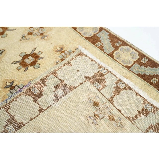 The sandy cream field shows a modified Turkmen allover design of aina guls and chemche guls, in five offset columns,...