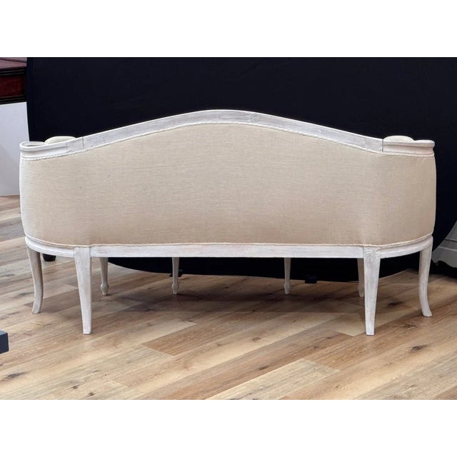 An elegant Swedish Gustavian canapé, settee, circa 1800–1830, featuring a gently arched back and open arms terminating in...