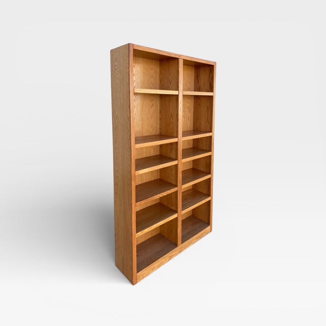 A tall vintage oak bookcase with a balanced double-column layout, warm natural finish, and open shelving for books,...