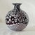 A beautiful hand-blown art glass vase featuring a rich dark purple base accented with white confetti-style speckling...