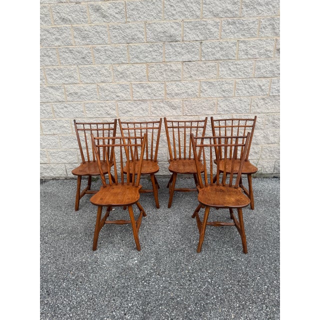 A set of six vintage Windsor-style dining chairs, including four side chairs and two armchairs. Crafted from solid wood,...