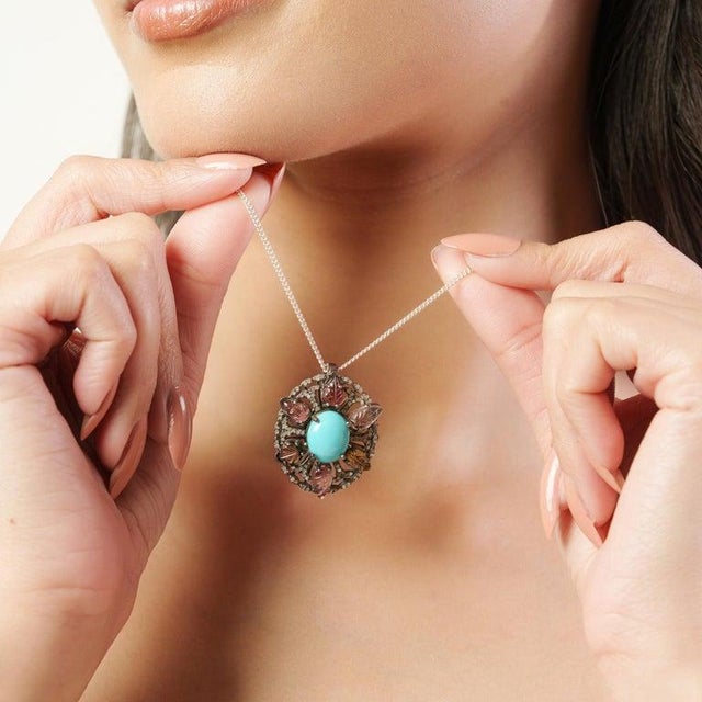 This elegant 925 sterling silver pendant features a striking natural turquoise oval cabochon (12×10 mm) at the center,...