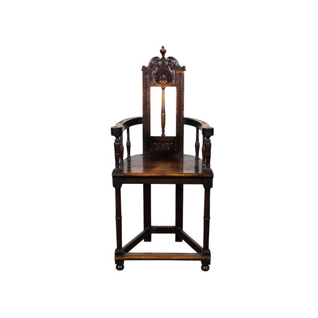 High-back carved wooden armchair. Turned legs and box stretcher. Hand carved crest rail. Scrolled arms with floral motifs.