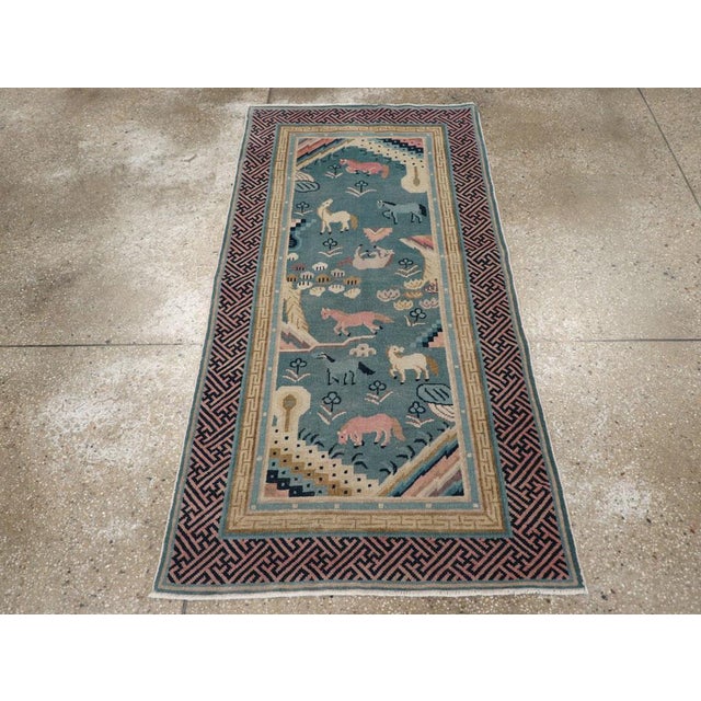 This early 20th century Chinese Peking Art Deco rug, presents a captivating pastoral scene woven with charm and artistry....