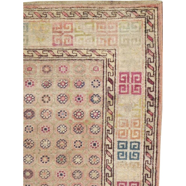 A Classic early 20th century Indian Agra, daisy style flowers set on a beige field, encased by angular hook ornament style...