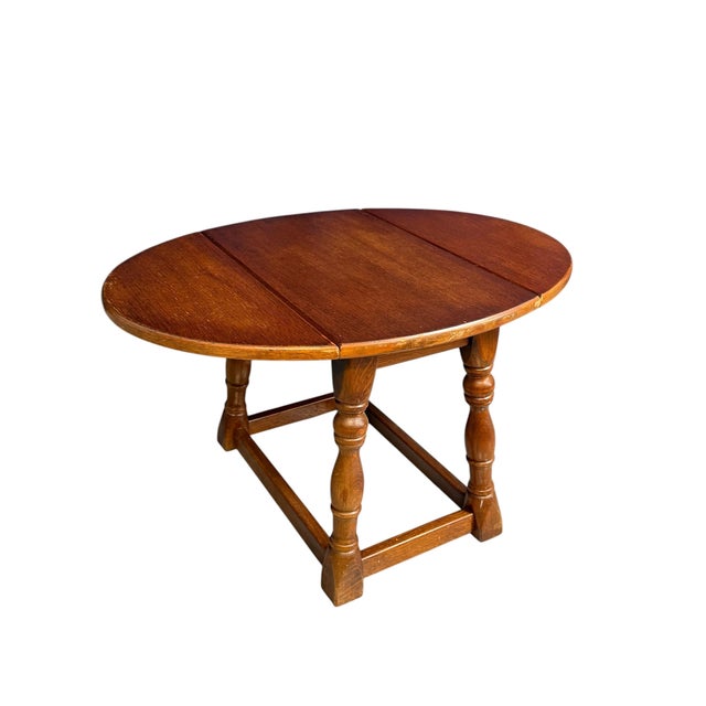 Antique miniature oak drop-leaf table featuring traditional turned baluster legs and a sturdy box stretcher base. This...