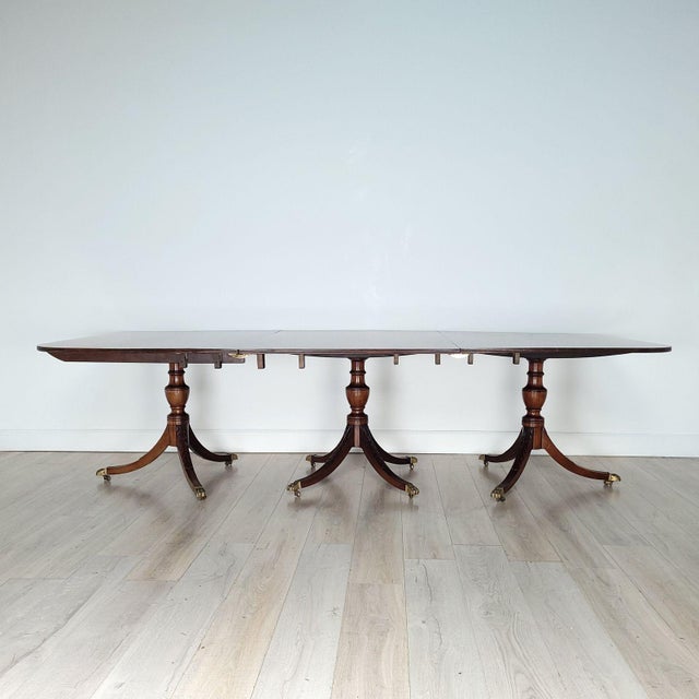 A large three-pedestal English dining table in mahogany with satinwood, with four leaves, 19th century and later. Measures...
