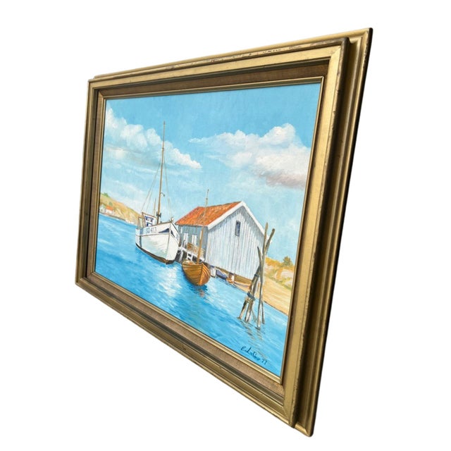 Harbor scene with a moored sailboat, a small dinghy, whitewashed boathouse with terracotta tile roof and one window....