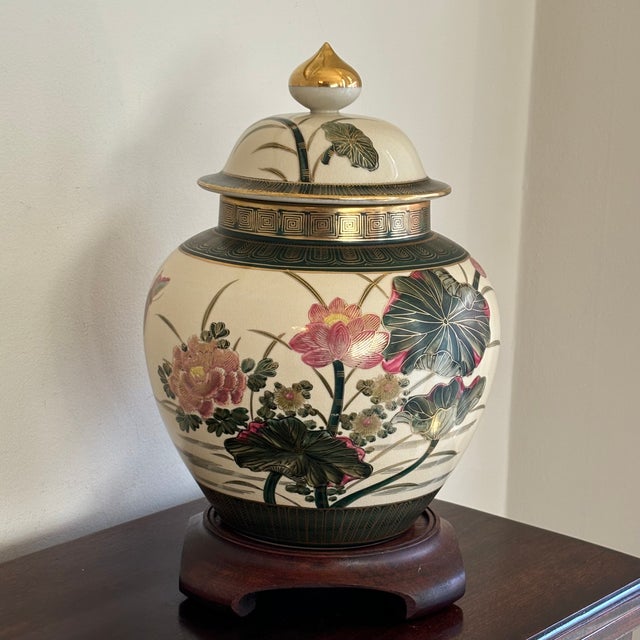 A striking late-20th century porcelain ginger jar showcasing a lush lotus pond scene rendered in raised enamels and hand-...