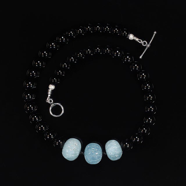 This striking 18‑inch necklace showcases a sophisticated blend of deep, glossy black onyx and the serene, ocean‑washed...