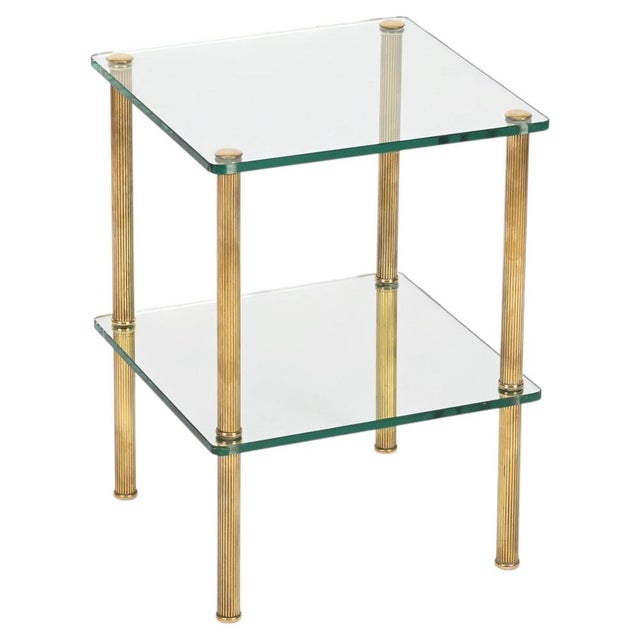 Elegant and unique two-tier side table in solid brass and thick crystal glass. This stylish piece was produced in France...