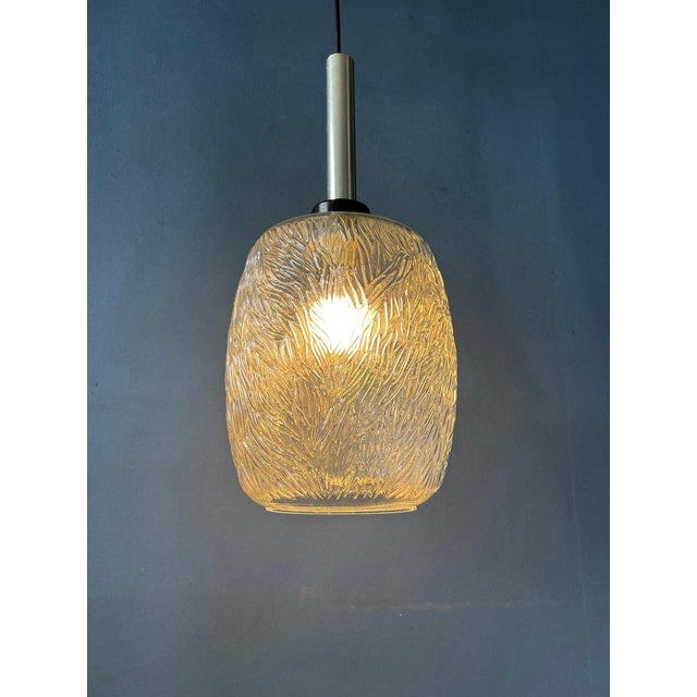 Mid-Century clear glass pendant lamp with leaf-like pattern. The patterned glass fractures the light, spreading it...