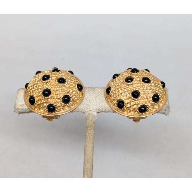 1980s round domed goldtone textured studded with cabochon faux-onyx clip earrings. Marked "Guy Laroche" on the clips and...