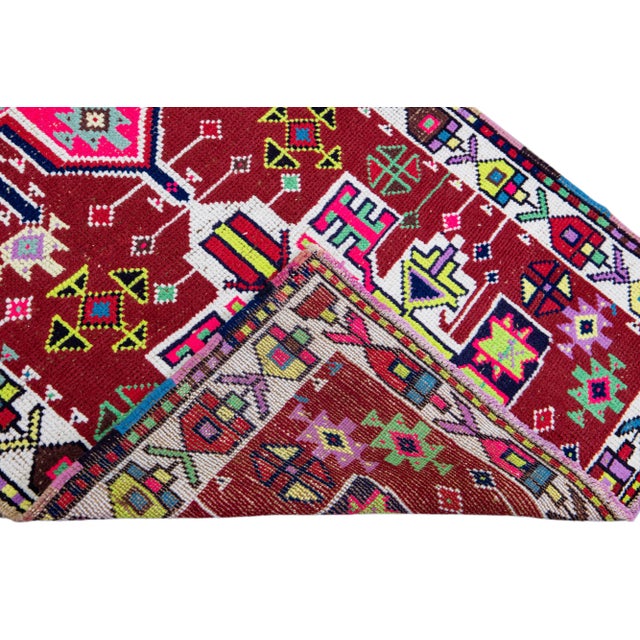 Beautiful vintage Turkish hand-knotted wool rug with a red field. This rug has a white designed frame and multicolor...