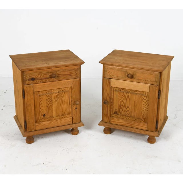 A pair of Scandinavian pine nightstands dating to the 1970s. Each nightstand features a compact cabinet form with a single...