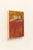 This artwork depicts a contemplative figure reclining against a backdrop of warm orange and deep red hues, creating a...
