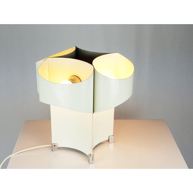This 4-lights table lamp was designed in Italy in the 1960s. It is made of chrome-plated metal and bent painted metal; the...