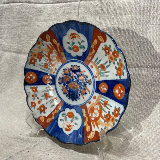 19th Century Japanese Imari plate. Hand painted with red orange, cobalt blue, and green on a white ground. The central...
