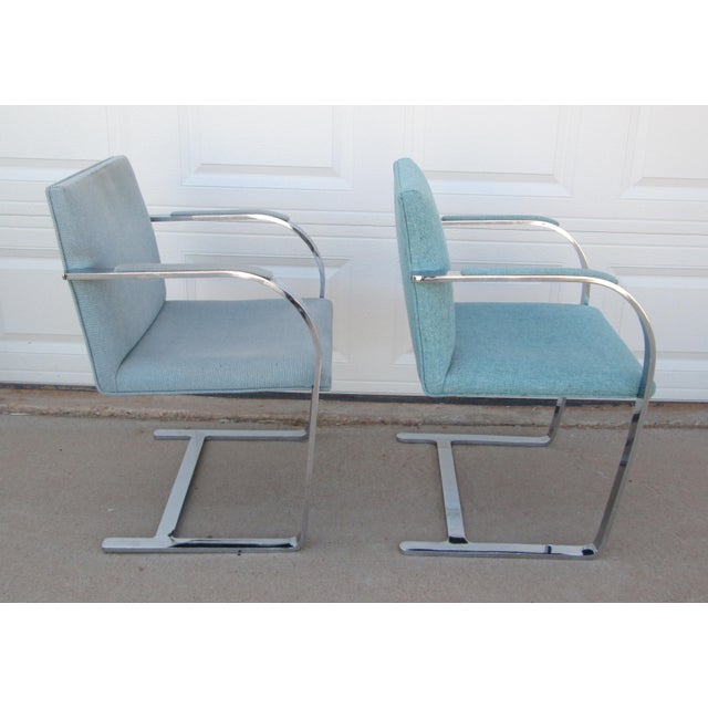 2 Brno style chairs (designed by Ludwig Mies van der Rohe) with flat arm silver tone metal and blue fabric. The chairs are...