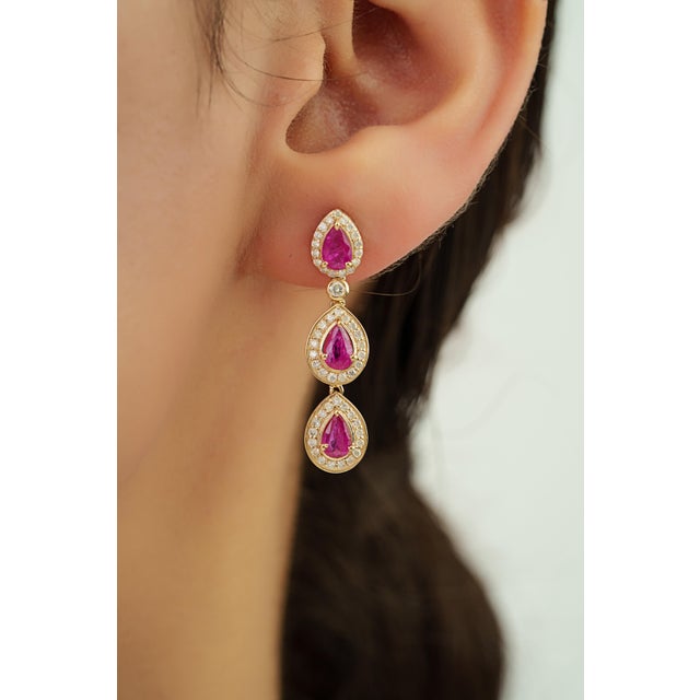 These drop earrings feature 2.05 carats of pear-cut Mozambique rubies set in 14K yellow gold. The ruby measuring 3.5 x 5.5...