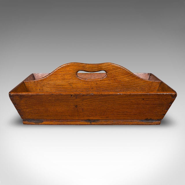 This is an antique housekeeper’s carry. An English, oak two-division cutlery tray, garden trug or work box, dating to the...