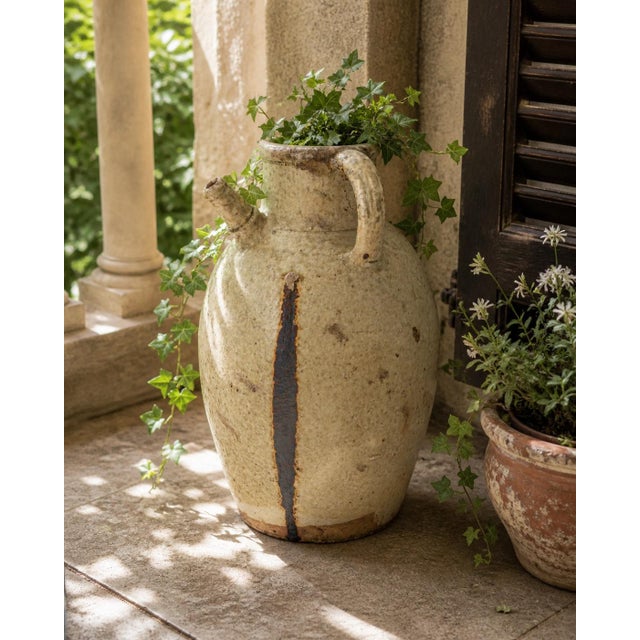 Large late 19th century French terracotta confit jug featuring the traditional double handle form and warm cream glaze...