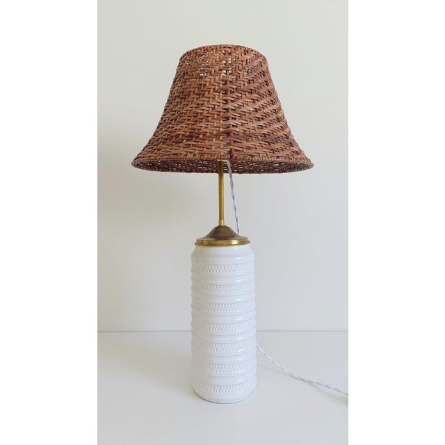 Ceramic table lamp with carstens tönnieshof base, brass detail, and wicker shade a refined table lamp composed of high-...
