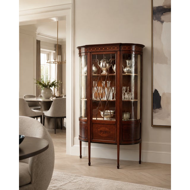 An antique Edwardian mahogany inlaid display cabinet with bowed glass ends, decorative astragal glazing and an elegant...