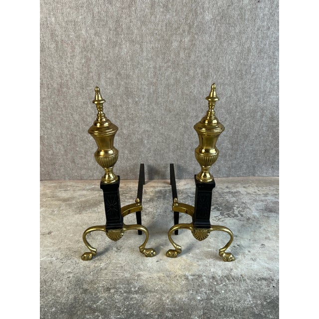 Vintage pair of French Empire or Regency Style brass and black cast iron, steeple top andirons with lion’s paw feet. This...