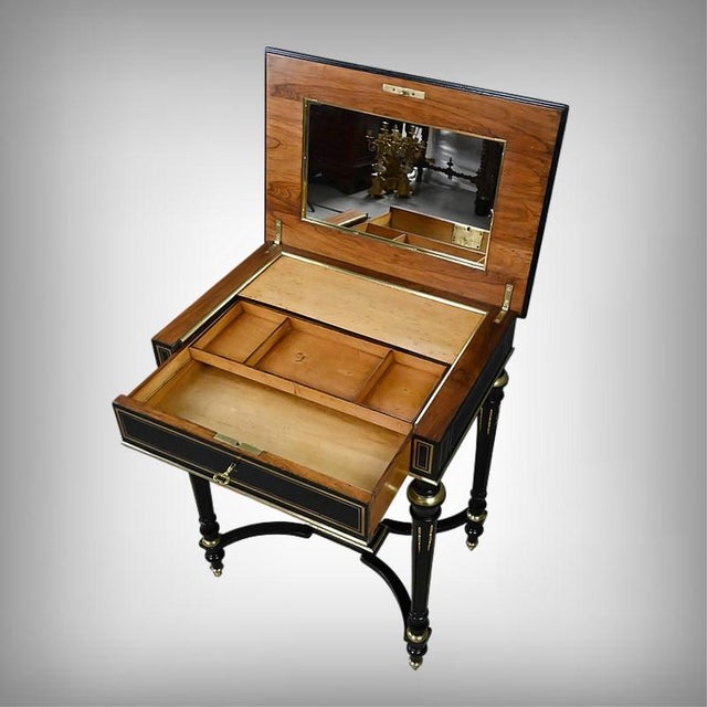 This Napoleon III period sewing table, crafted from ebonized wood, is distinguished by its delicate marquetry of brass...