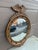 A gorgeous Federal or Regency style convex bullseye wall mirror featuring a carved eagle with open wings standing on olive...