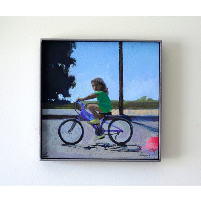Traces captures a moment of childhood innocence as a young girl rides her bicycle, her expression a mix of concentration...