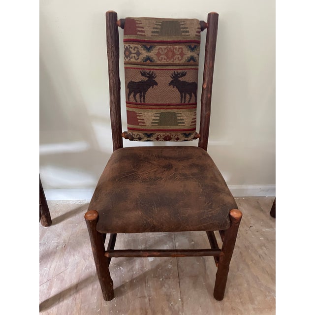 Rustic Old Hickory Adirondack style chairs, 8 total. Tapestry fabric back and leather-look seat. Side chairs are 19 1/2”...