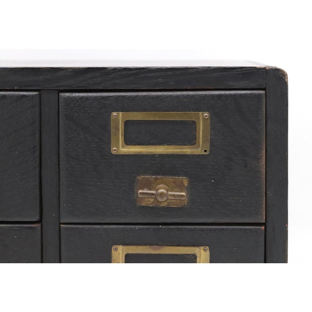 Vintage oak wood four drawer tabletop card file, painted black, with brass label holders and pulls on each drawer. The...