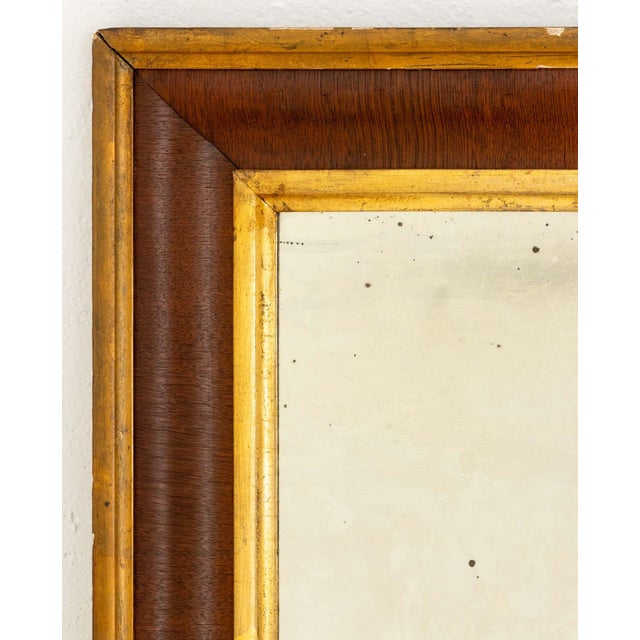 American Gilt Trim and Mahogany Framed Mirror. Mirror plate: 26" H x 14.75" W; frame: 34.25" H x 23" W x 2" D. Provenance:...