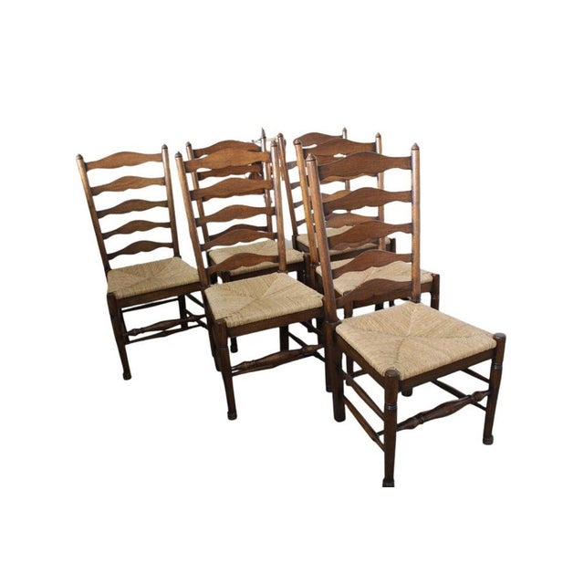 Classic set of six vintage ladderback side chairs featuring handwoven rush seats and traditional slat-back design. Crafted...