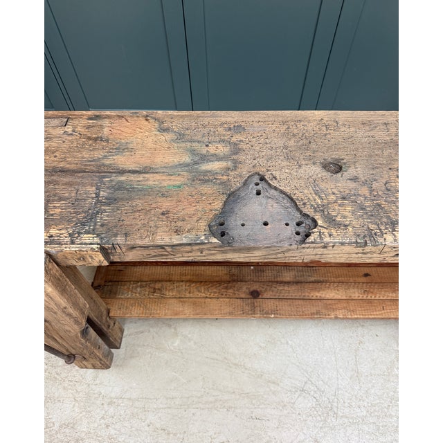 This antique solid oak carpenter's workbench likely dates from the first half of the 20th century. Bearing the marks of...