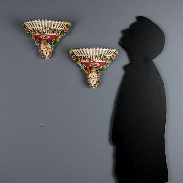 Pair of polychrome porcelain wall vases. Decorated with allegories of children surrounded by flowers. Against a pink...