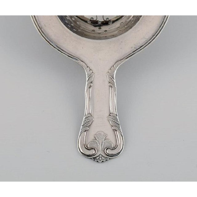 Cohr tea strainer in silver. Mid-20th century. Measure: Length: 14.3 cm. Stamped. In excellent condition. Our skilled...