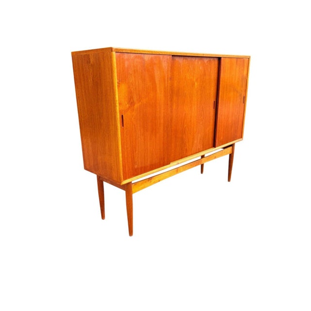 A striking tall Danish modern cabinet from the 1960s, distinguished by its two-material construction: teak door panels and...