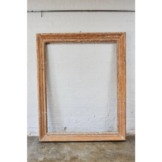 This large frame was originally heavily carved and gilded and now has a simplified, rustic surface with remnants of gilt...
