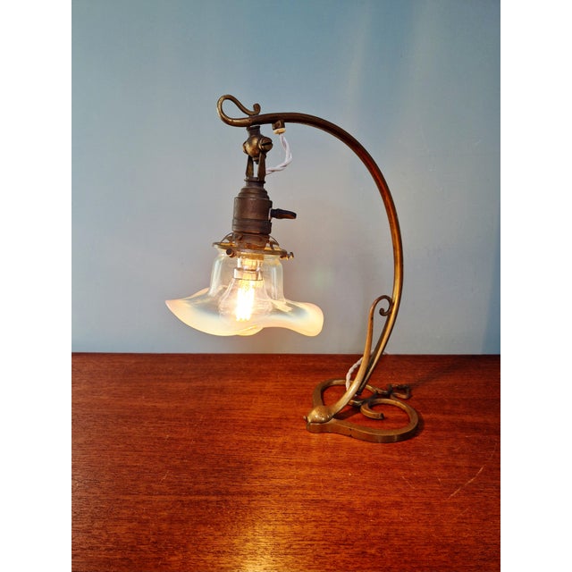 Art Nouveau table lamp in bronze and brass with an opalescent glass shade, circa 1900. This articulated lamp has been...
